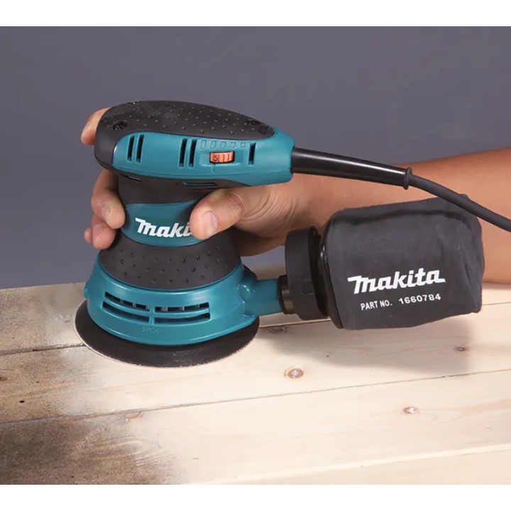 Levigatrice orbitale MAKITA BO5031K in uso su superficie in legno